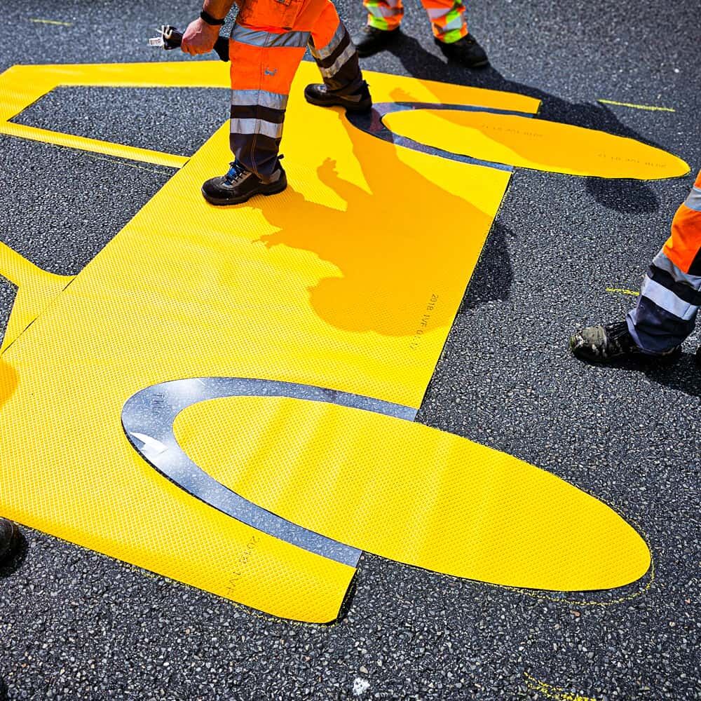 Straßenmarkierer verlegen Pkw-Symbol aus 3M Stamark auf frisch gereinigtem Asphalt