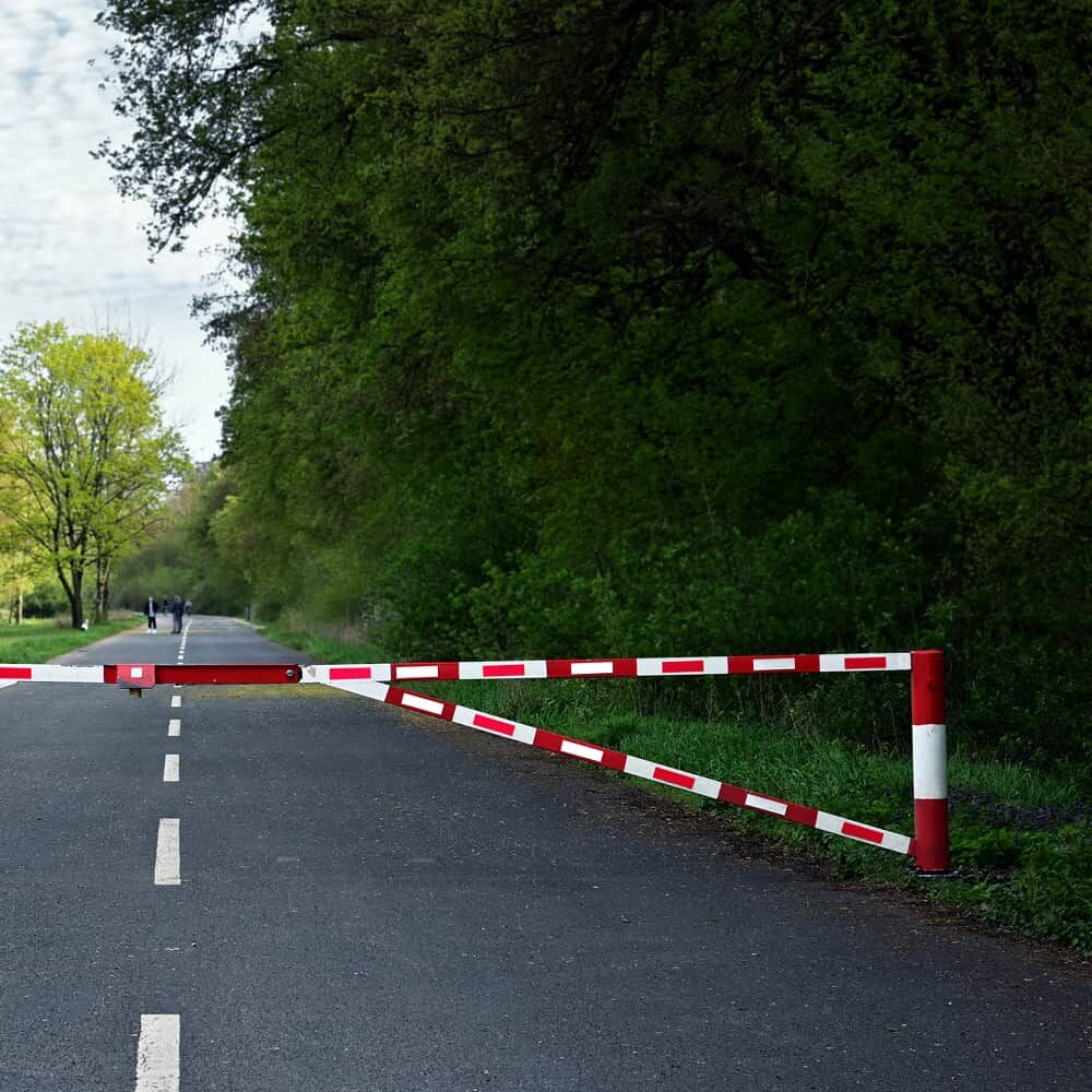 Forststraßenschranke mit rot-weißen 5810-Reflexstreifen sperrt Asphaltweg