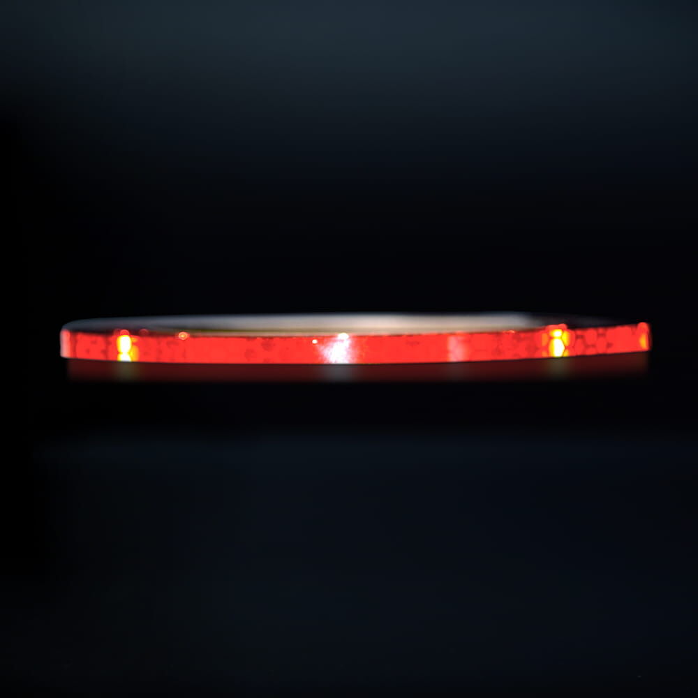 5 mm Rolle Avery Reflexband V-8000 rot, reflektierend vor dunklem Hintergrund