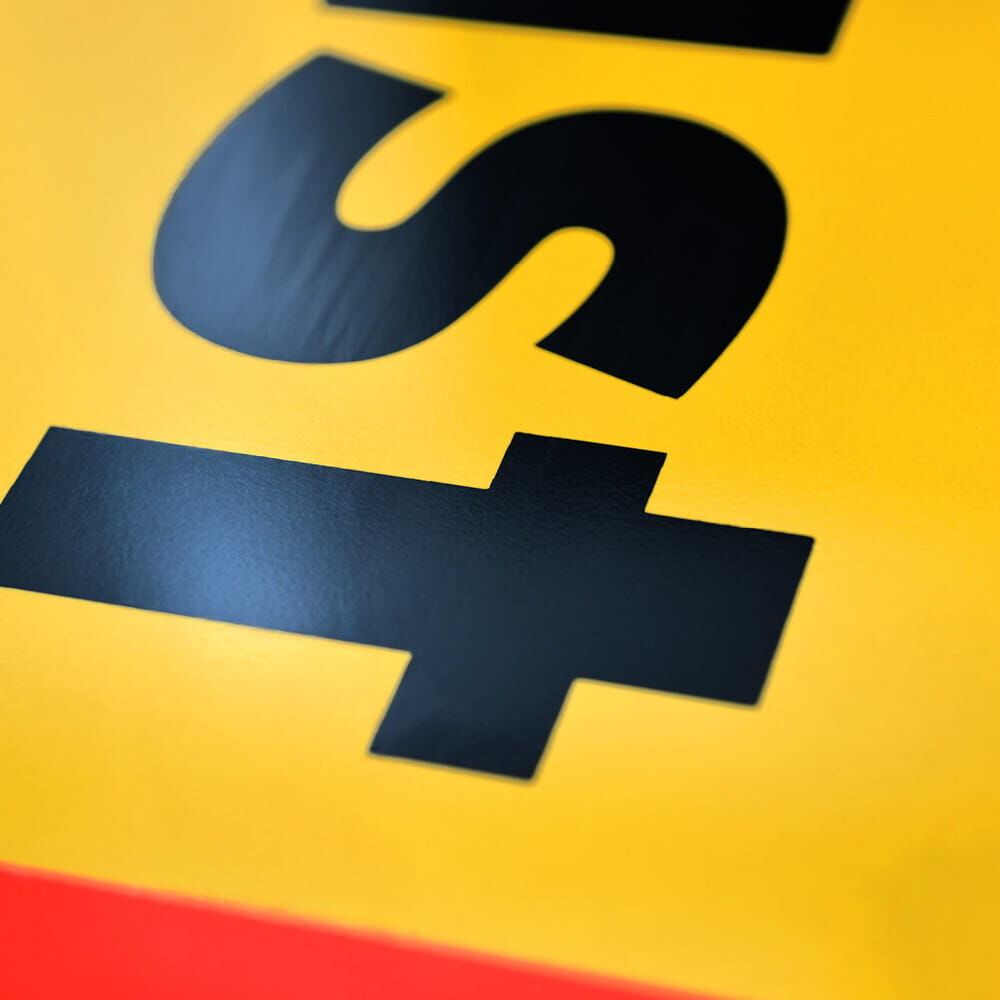 Detailaufnahme schwarzer Schrift auf gelbem Untergrund