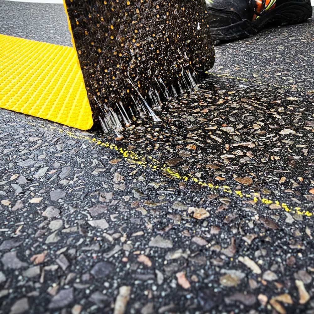 Rückseite der 3M Stamark Fahrbahnmarkierung, mit Klebstoffspikes beim Abziehen vom Asphalt sichtbar