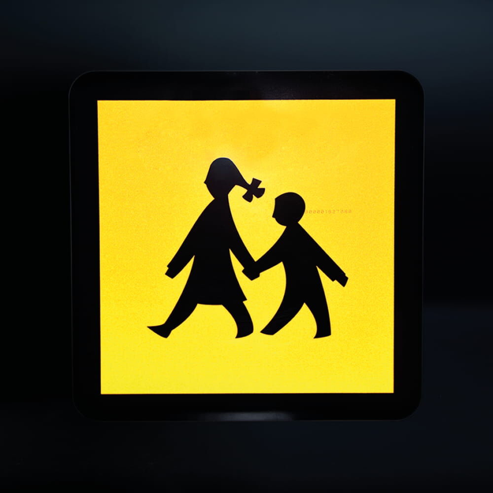 Schulbusschild reflektiert bei Dunkelheit im Lichtschein deutlich