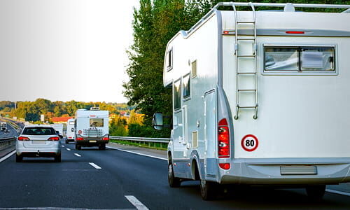 Abschnittstitelbild zu Geschwindigkeitsschildern Das Titelbild der Themenseite Caravan zeigt ein Wohnmobil aus Heckperspektive mit maximal 80kmh Geschwindigkeitsschild auf der Autobahn