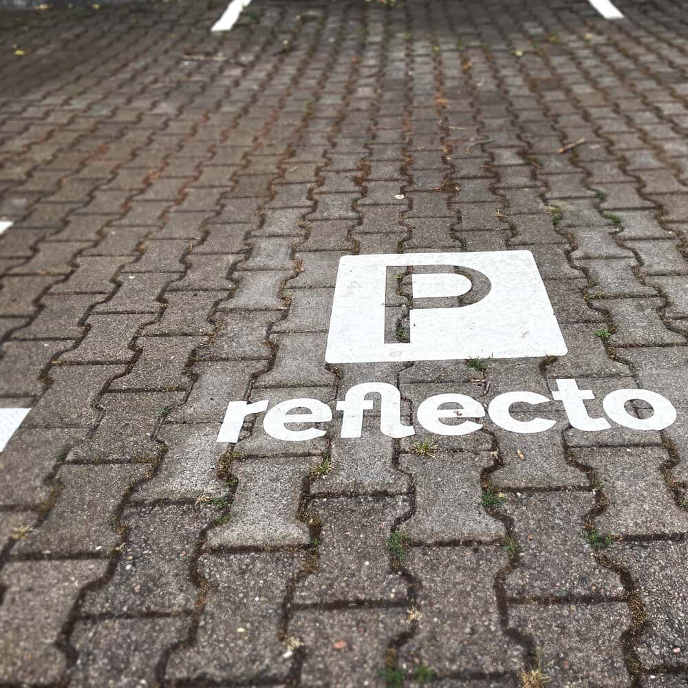 Weiße 3M Stamark Parkplatzmarkierung „P reflecto“ auf Pflasterfläche