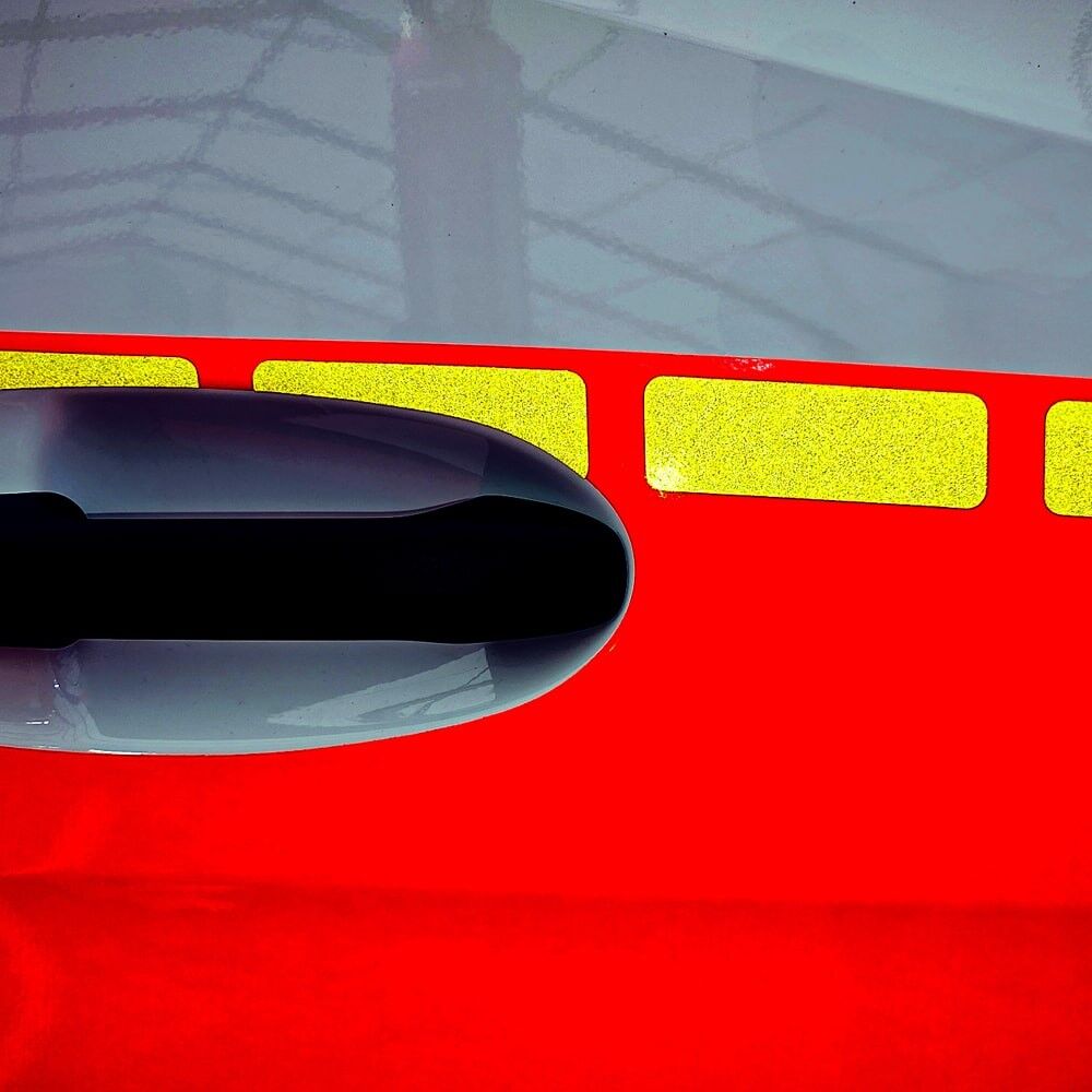 Detailansicht reflektierender gelber Markierungssegmente bei Lichteinfall neben einem Türgriff