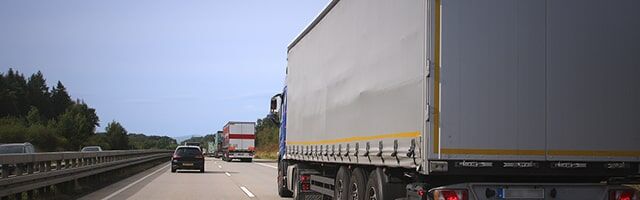 Konturmarkierung – Markierungsarten Seitenansicht eines LKW-Anhängers mit Planenverdeck und gelber Konturmarkierung auf einer mehrspurigen Autobahn