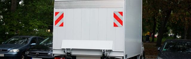 Warnflaggen für Hubladebühnen gemäß § 53 StVZO Rückseite eines weißen Transporters mit rot-weißen Warnflaggen in den oberen Ecken