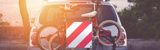 Ein Auto, das ein Fahrrad auf dem Heck montiert hat, ausgerüstet mit einer Italien-Warntafel davor steht bereit für Reisen durch die Toskana.