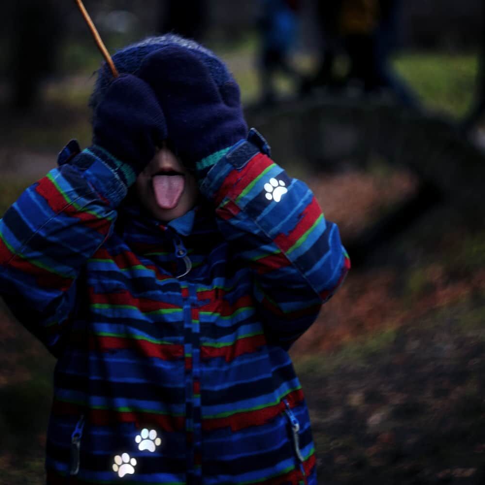 Kind in bunter Jacke mit reflektierenden Pfoten-Bügelbildern an Ärmel und Saum