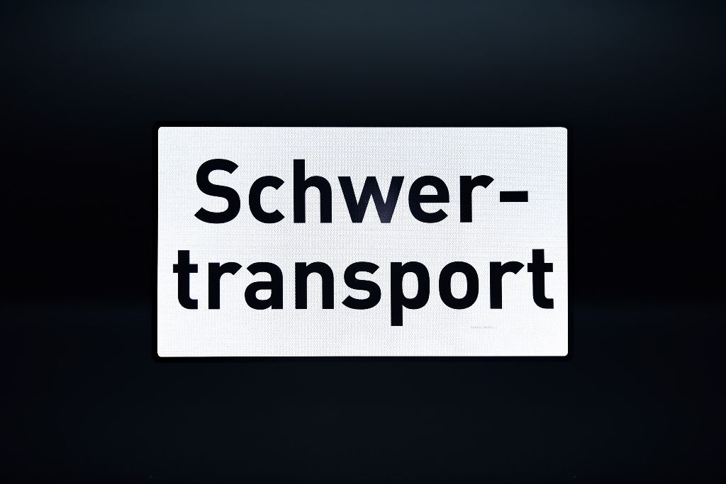 Reflektierendes Schild „Schwertransport“ vor dunklem Hintergrund