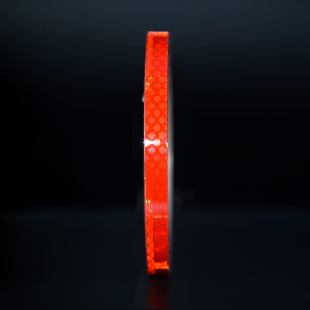 10 mm Rolle 3M Reflexband 3930 rot, reflektierend vor dunklem Hintergrund