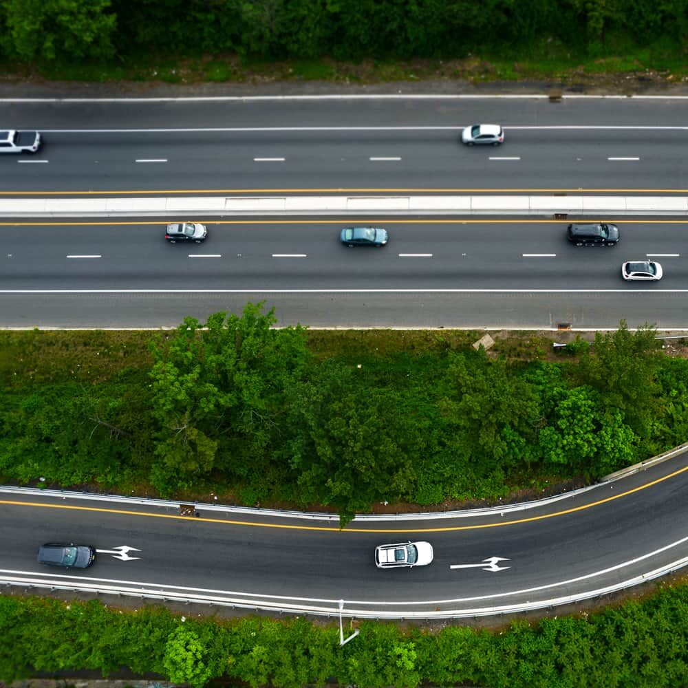 Luftaufnahme von Autobahnauffahrt mit weißer Richtungspfeil-Markierung auf Asphalt