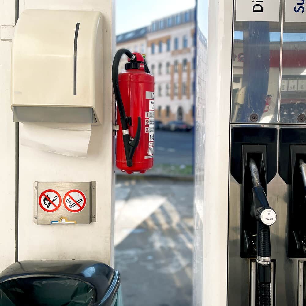 Anwendung des Aufklebers „Rauchen verboten“ an einer Zapfsäule neben Feuerlöscher