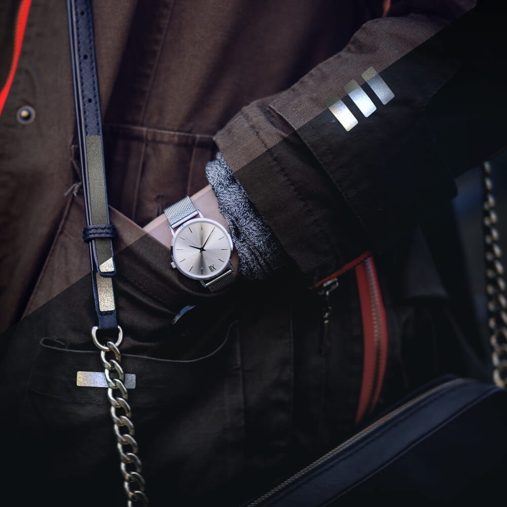 Jacke mit drei Metallic-Reflexstreifen: Tagansicht links, Nachtreflexion rechts nebeneinander.